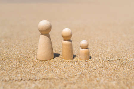 Wooden three figures of people on the sand of the beach with sea view. Concept of happy family with two kids on holiday.の写真素材