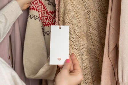 Woman customer looking on tag choosing sweater with christmas ornament in garment store. shopping. Winterの写真素材