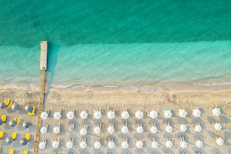 Aerial view of many white sunbed, lounge, umbrellas on sandy beach. Summer and travel concept. Blue, turquoise transparent water surface of ocean, sea, lagoon. Aerial, drone viewの写真素材