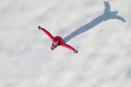 Happy woman, girl in a red winter jacket with spreading her arms standing on snow covered land ....