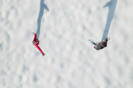 Man and woman (couple) playing snowballs on the snow in a park. Winter. Drone, top, aerial view.の写真素材