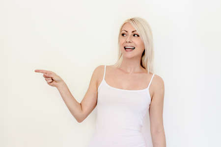 Cute young woman pointing and looking to the side. Gorgeous race caucasian model. Isolated on white background.adorableの写真素材
