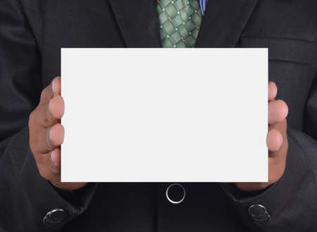 Businessman holding card in black suit isolated on white backgroundの写真素材