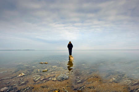 A person standing on a rock looking out over the Chesapeake Bay in Maryland surrounded by waterの写真素材