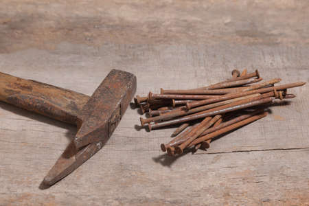 old and rusty claw hammer and nails on a wooden workbenchの写真素材