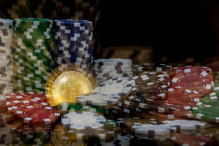 golden bitcoin in front of stacks of  white green blue and red gambling chips zoomed into the coin in the middleの写真素材