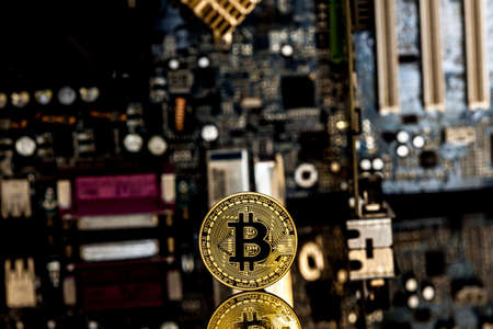 Golden bitcoin in front of a  motherboard dynamically zoomed into the bitcoin concept for crypto currencyの写真素材