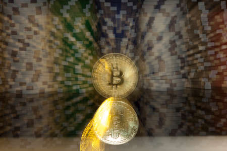 golden bitcoin in front of stacks of  white green blue and red gambling chips zoomed into the coin in the middleの写真素材