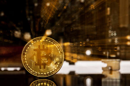 Golden bitcoin in front of a  motherboard dynamically zoomed into the bitcoin concept for crypto currencyの写真素材