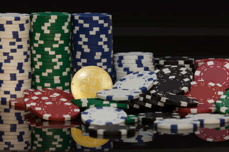 golden bitcoin in front of stacks of  white green blue and red gambling chips zoomed into the coin in the middleの写真素材