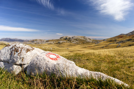 Mountain landscape with a sign on a rock in the foreground.の写真素材