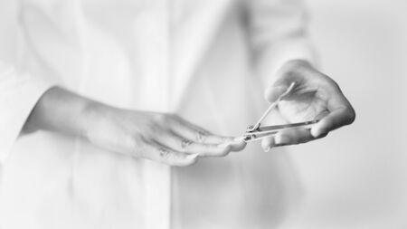 monochrome shot of a woman cutting her nails with shallow depth of field, focus on nail clipperの写真素材