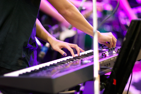 hands of musician playing keyboard in concert with shallow depth of field, focus on left handの写真素材
