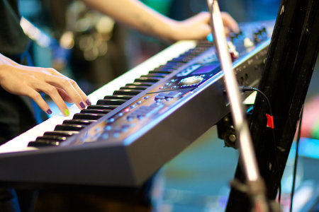 hands of musician playing keyboard in concert with shallow depth of field, focus on right hand