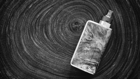 black and white, monochrome shot of high end stabilized wood regulated box mods with rebuildable dripping atomizer on wood texture background, vaping device, selective focus on attyの写真素材