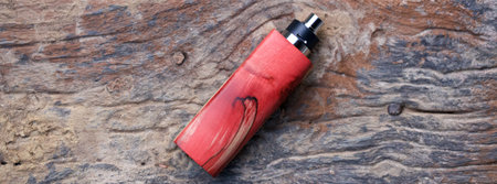 high end red natural stabilized wood box mods with rebuildable dripping atomizer on old wood texture...