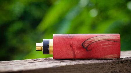 high end red and natural stabilized wood box mods with gold and black rebuildable dripping atomizer, vaporizer equipment, selective focusの写真素材
