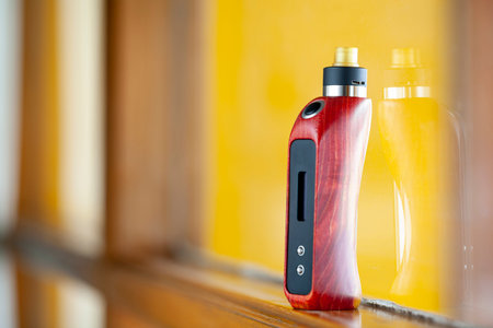 high end rebuildable dripping atomizer with red and black stabilized wood box mods on natural wood,...