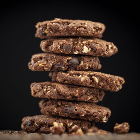 stack of chocolate chip and oakmeal cookies on natural wood texture on black background, selective focus, square ratio, 1 x 1の素材 [FY310135050788]