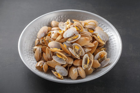fresh steamed baby clam in metal plate on dark texture background, easy seafood recipe menu