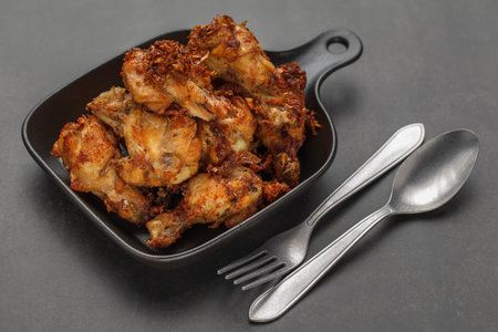 fried chicken with black pan on the dark tone texture background
