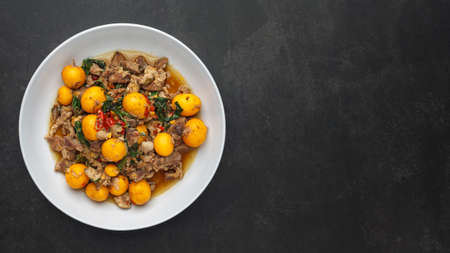 hot and spicy stir fried chicken ovary egg with chicken entrails and basil on dark grey texture background with copy space, Thai local street foodの写真素材