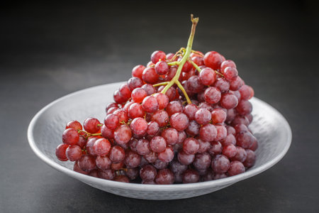 fresh red grape in nice metal plate on dark grey tone texture background