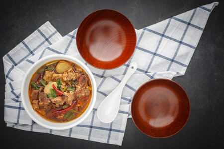 Tom Yum, Thai food, hot, spicy and sour stewed beef soup in bowl with white ceramic spoon, empty...