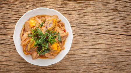 Pad Ka Prao Kai Yeow Ma, Thai food, basil stir fried century egg and sliced pork with crispy basil leaves on top in ceramic plate on rustic natural wood texture background with copy space, top viewの写真素材