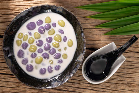 Bualoy, Bua Loy, Bualoi, Bua Loi, Thai dessert, sticky rice dumplings in sweet coconut milk, purple color from taro, green color from pandan leaf on rustic natural wood texture background, top viewの写真素材