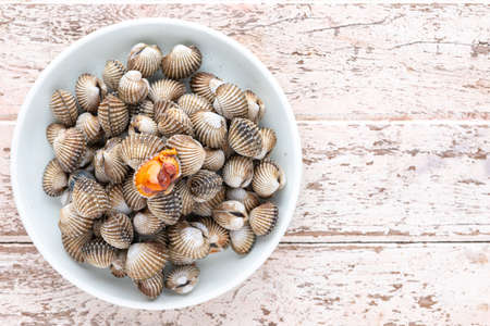 fresh steamed cockles, boiled cockles in ceramic plate on old white wood texture background with copy space for text, top view, light and airy food photography, blood cockleの写真素材