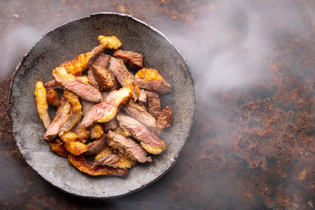 hot juicy sliced grill beef fillet steak meat in wabi sabi style plate on rusty texture background with somke, top view, flat lay, copy space for textの写真素材