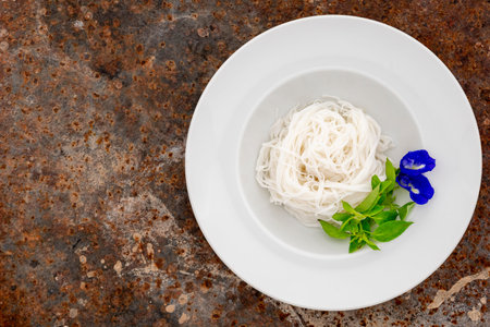 Thai vermicelli, Thai rice noodles, Kanom Jeen with Hairy Basil leaves and Butterfly pea flowers in...