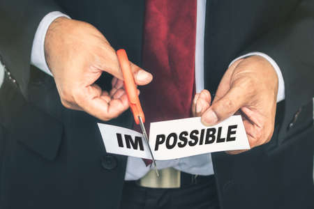 Closeup businessman cutting paper of impossible wordの写真素材