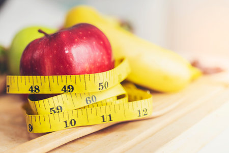 Yellow measuring tape surrounded by red apples.Health Care and Weight Management Concepts