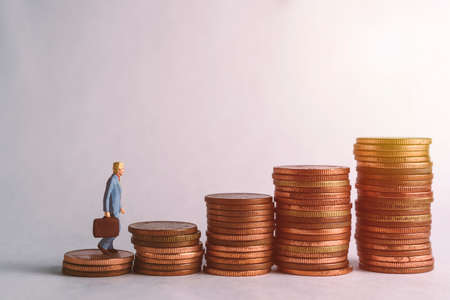 A businessman's doll is standing on coins for collection (Coins Thailand), business concept.の写真素材