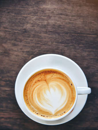 Coffee with heart-shaped cream, white cup on the wood table.の写真素材