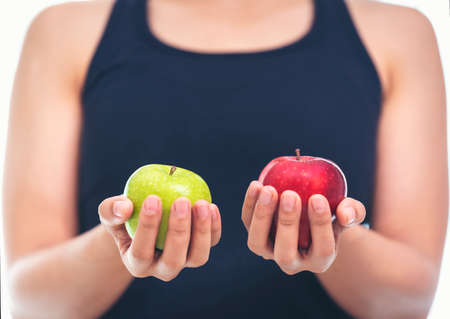 A woman in a fitness suit is holding an apple green and red.Healthy Eating Concept.Focus on apple.の写真素材
