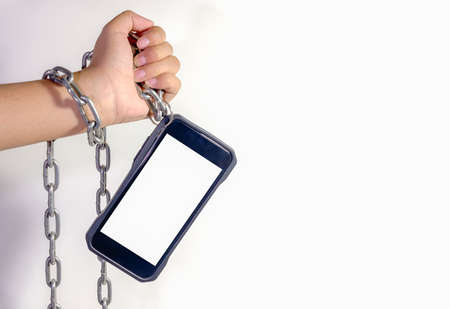Hands chained holding smartphone.It is indispensable in daily life.の写真素材