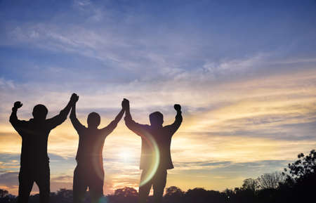 Teams that are willing to share success, stand together, hold hands, look to the sunset the background.Silhouette imageの写真素材