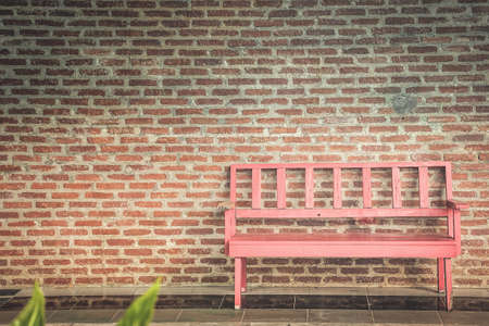 The red bench and the brick wall are the background.の写真素材