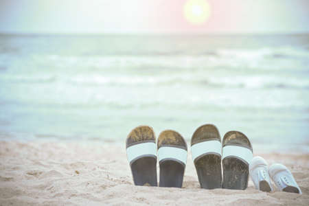 Slippers of the family on the beach and the sea as the background blurred.の写真素材