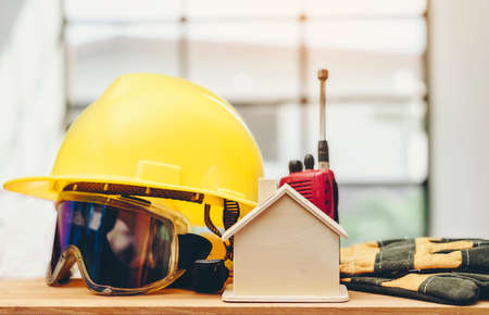 Wooden replicas, yellow helmets and accessories are placed on wooden floors.Standard and safe construction concept.の写真素材