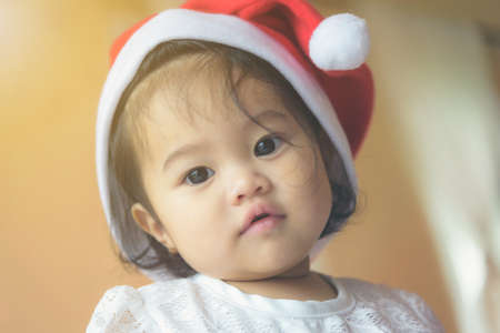 Little Asian girl wearing a Santa Cross hat. Has a cute and innocent look.の写真素材