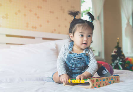An Asian baby girl is playing in her bed with a happy expression.の写真素材
