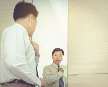 Business men are shining a mirror, dressing up a costume to work out. A daily routineの写真素材