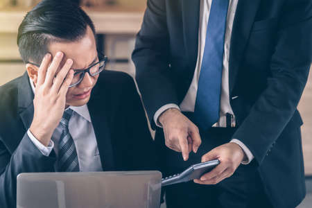 Male business man is being blamed by a boss who holds a calculator.の写真素材