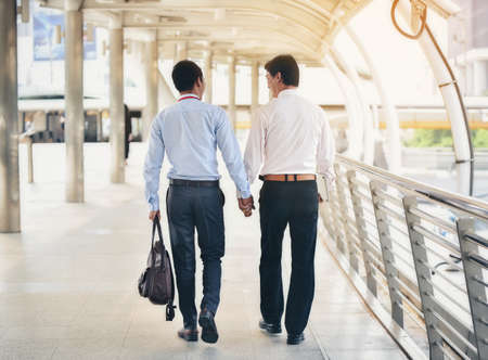 Two Asian business men are walking hand in hand and taking care of each other.The concept of sex couples is correct according to the rights of each person.の写真素材