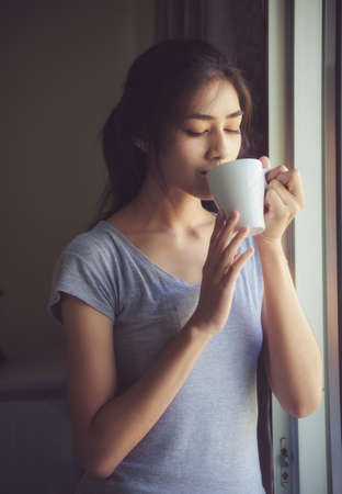 Lovely women are drinking coffee happily on weekends with a light sunshine by the window. Life style conceptionの写真素材
