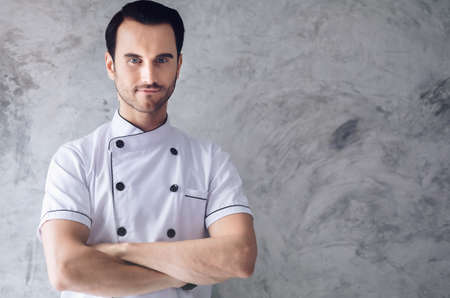 The chef is handsome, smiling and confident with a plastered background.の写真素材